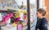 Woman looking at hats through window.