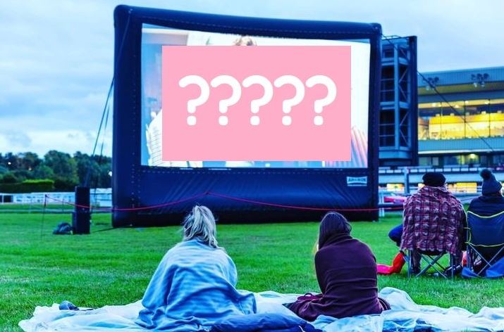 People sat outside watching a film on inflatable screen.
