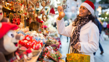 Woman shopping for gifts at outdoor Christmas market.